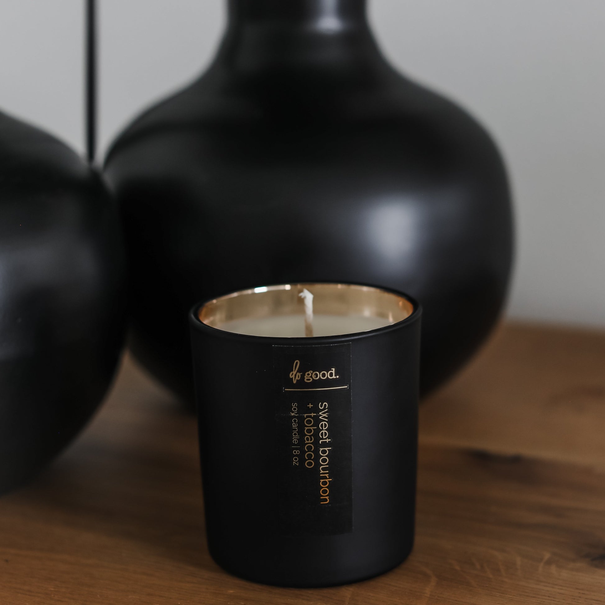 picture of a soy candle named sweet bourbon + tobacco poured into a matte black vessel with gold electroplated interior