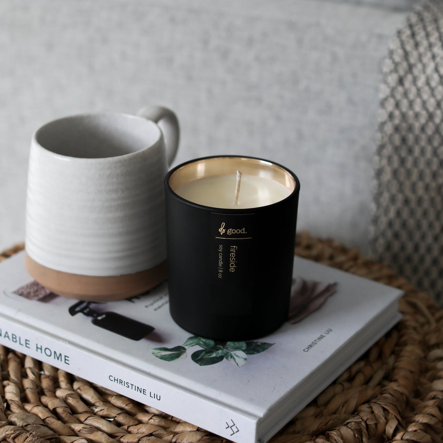 photo of soy candle called fireside sitting on a table and book next too a coffee mug