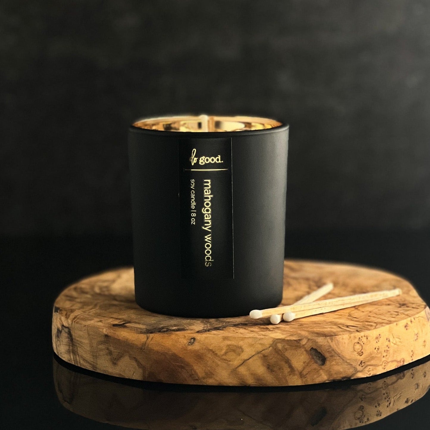 soy candle named mahogany woods in a matte black vessel with a gold electroplated interior