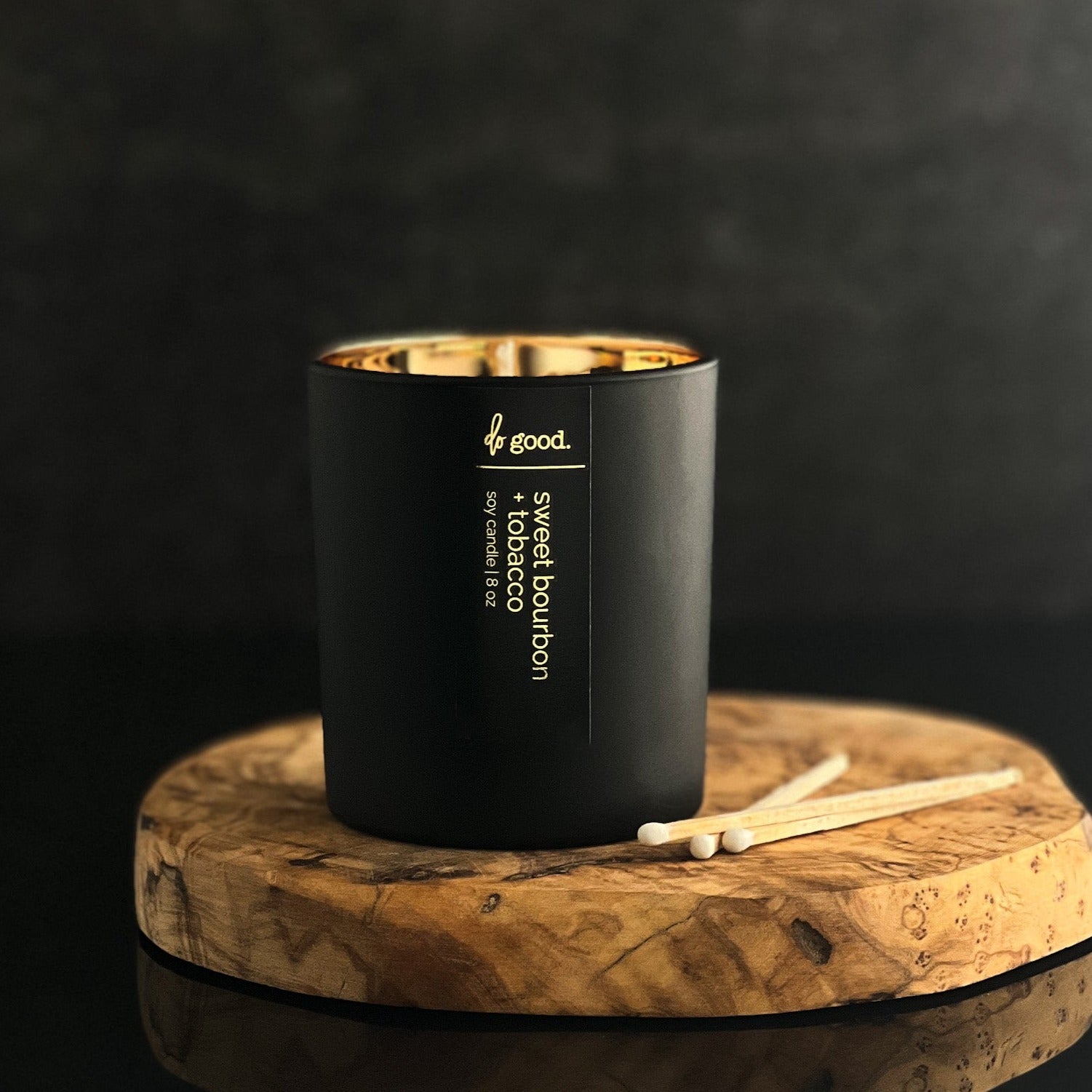 picture of a soy candle named sweet bourbon + tobacco poured into a matte black vessel with gold electroplated interior